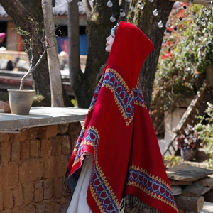 Détail du châle ethnique à capuche avec motifs rouges et bleus et franges noires