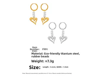 Détail de boucles d'oreilles cœur en or et argent avec des perles blanches en acier
