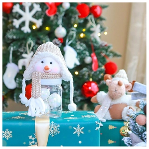 Detailed view of a Christmas snowman candy jar with a knitted hat on a festive gift box