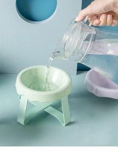 Close-up of mint green elevated cat bowl with cross stand and water pouring detail