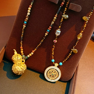 Detail of tiger eye and turquoise beaded necklaces with gold gourd and floral pendants