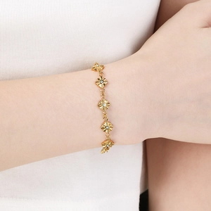 Dettaglio di un bracciale dorato con stella a otto punte e pietre portafortuna al polso