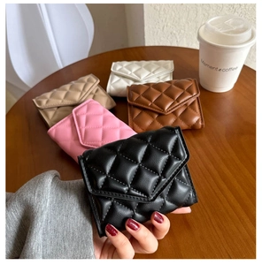 Multiple quilted leather wallets in various colors on a wooden table for women