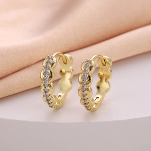 Close-up of gold huggie earrings with wavy edges and sparkling cubic zirconia stones