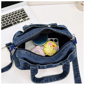 Detail view of the blue denim kid's crossbody bag capacity with open zipper and strap
