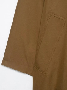 Detail of caramel brown trench coat showing high-quality twill fabric and stitching