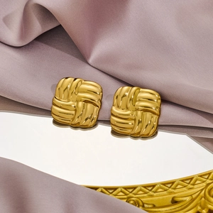 Elegant gold woven texture square stud earrings set on a reflective vintage mirror