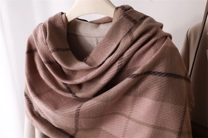 Detailed texture of brown plaid cashmere-like scarf with soft fringes and classic pattern