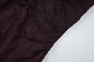 Gros plan détaillé montrant la texture florale complexe du tissu en dentelle violet foncé