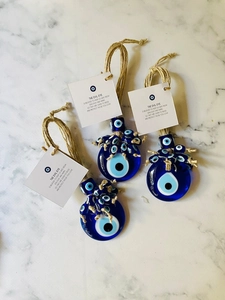 Close-up of three Turkish blue glass evil eye pendants with woven hemp rope on marble