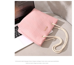 Detail of pink quilted tote bag with zigzag stitching, rope handles and metal logo