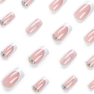 French tip press-on nails in nude pink with marble patterns and iridescent crystals