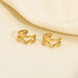 Detail shot of 18K gold double-layer ear cuffs with heart charm on beige silk cloth