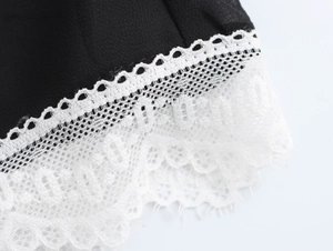 Detailed macro view of delicate white lace trim on the edge of a black chiffon dress fabric