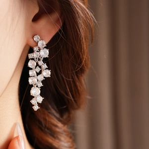Macro shot of silver tassel earrings with irregular zircons on model with soft lighting
