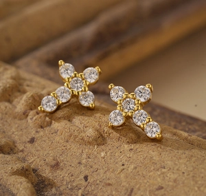Macro shot of gold S925 silver cross earrings with white cubic zirconia stones
