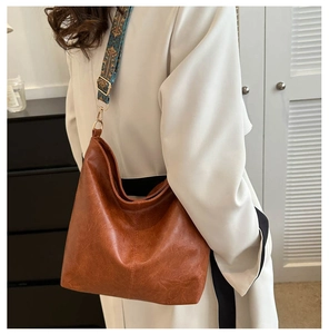 Close-up of wide geometric jacquard strap on vintage brown large faux leather tote bag