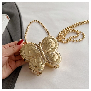 Close-up of golden butterfly shaped metal evening clutch with beaded chain strap