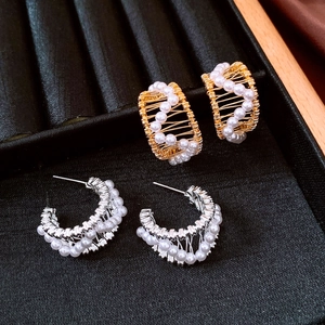 Detail of 18k gold plated pearl C-shape hoop earrings on black velvet jewelry tray