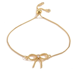 Detail of adjustable gold-plated bow bracelet with zircon stones and slider clasp