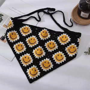 Detailed knit texture of handmade black crochet bandana with sunflower smile pattern