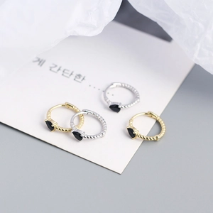 Detail of twist-textured gold and silver hoop earrings with black waterdrop stones