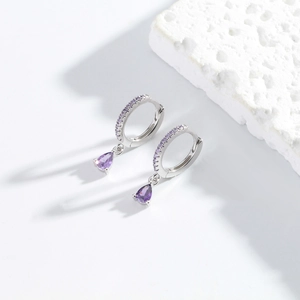 Detail view of S925 silver hoop earrings with purple teardrop zircon on white stone