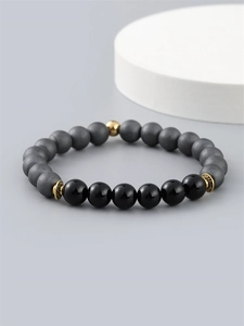 Men's beaded bracelet with hematite and obsidian stones on a modern gray display