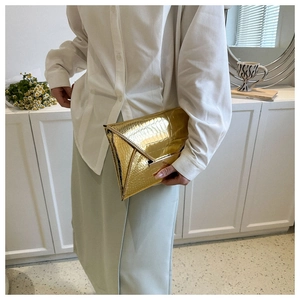 Close-up of golden crocodile texture envelope clutch bag with magnetic snap closure