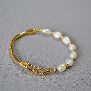 Detailed close-up of Baroque pearl and irregular gold-plated metal branch bracelet