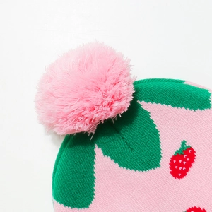 Close-up of a soft pink faux fur pompom on a strawberry patterned knitted beanie