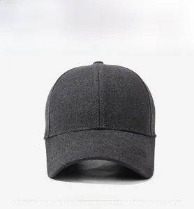 Vue de face d'une casquette de baseball en laine gris foncé avec plaque de logo en métal