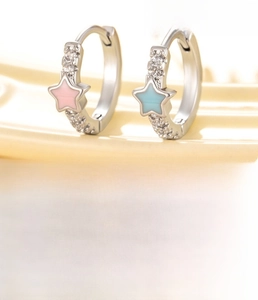 Macro shot of asymmetric pink and blue star earrings with white zircon accents