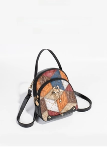 Detailed close-up of colorful patchwork mini backpack with swan pendant and gold rivets
