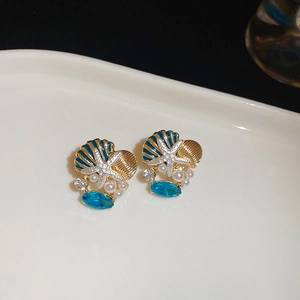 Detailed shot of starfish and seashell earrings with blue rhinestones and pearls on a tray