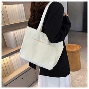 Close-up of a white corduroy tote bag with decorative pocket and XINRU GOOD logo design