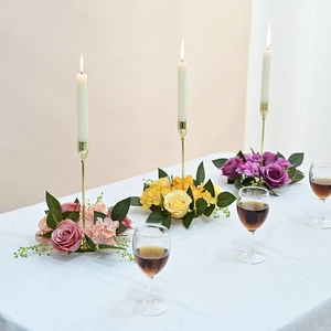 Detail of elegant gold candle holders with colorful rose and hydrangea floral wreaths