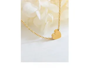 Close-up of a minimalist gold heart pendant necklace with a fine cross chain detail
