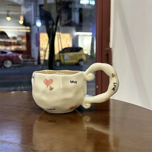 Detail shot of a handmade irregular ceramic coffee mug with Love heart and cream finish