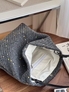 Detail of the gray knit tote bag showing the beige lining and internal zipper pocket