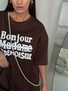 Detail of white Bonjour embroidery on premium brown cotton oversized t-shirt