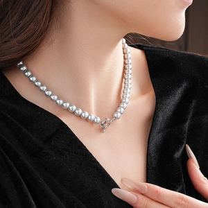 Close-up of grey pearl necklace with silver OT clasp worn on black velvet garment