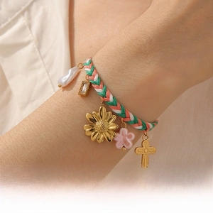 Detail of woven bracelet with colorful rope, gold sunflower, pearl, and floral charms