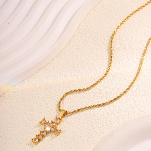 Detailed close-up of a golden cross pendant necklace with heart-shaped sparkling zircons