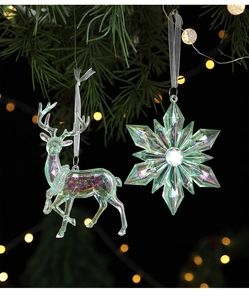 Close-up of iridescent acrylic reindeer and snowflake ornaments on a festive pine branch