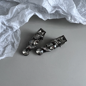 Detail shot of dark grey crystal hair clips with sparkling rhinestones on grey background