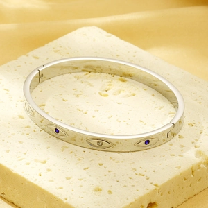 Macro shot of silver evil eye bracelet with blue zircons on stone and satin