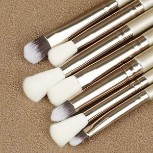 Macro detail of champagne gold eye makeup brushes with soft bristles on knit background