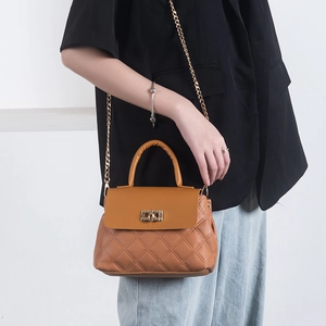 Brown quilted crossbody bag with gold chain strap and turn-lock closure on model