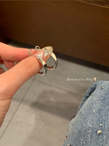 Close-up of polished silver C-shaped hoop earrings held by hand for detailed texture